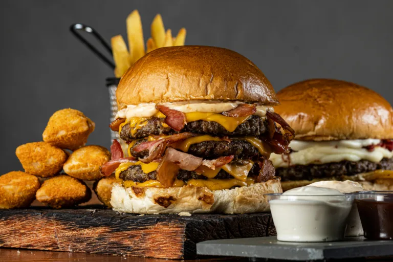 Tantalizing beef burgers with bacon, cheese, and sides elegantly plated.