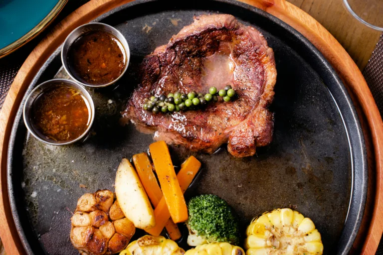 Delicious grilled steak served with vegetables on a hot sizzling plate, perfect for a gourmet meal.