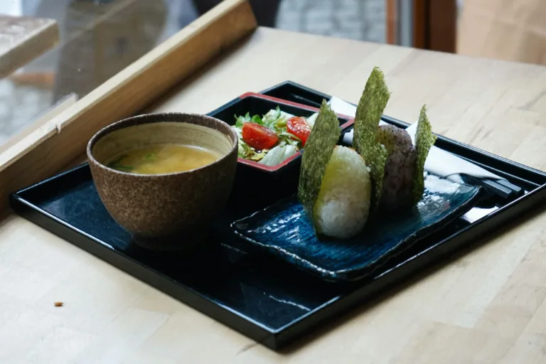 Delicious Japanese meal with onigiri, miso soup, and salad served indoors in Berlin.
