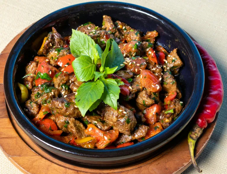Flavorful grilled beef stew with peppers and herbs served in a rustic bowl.